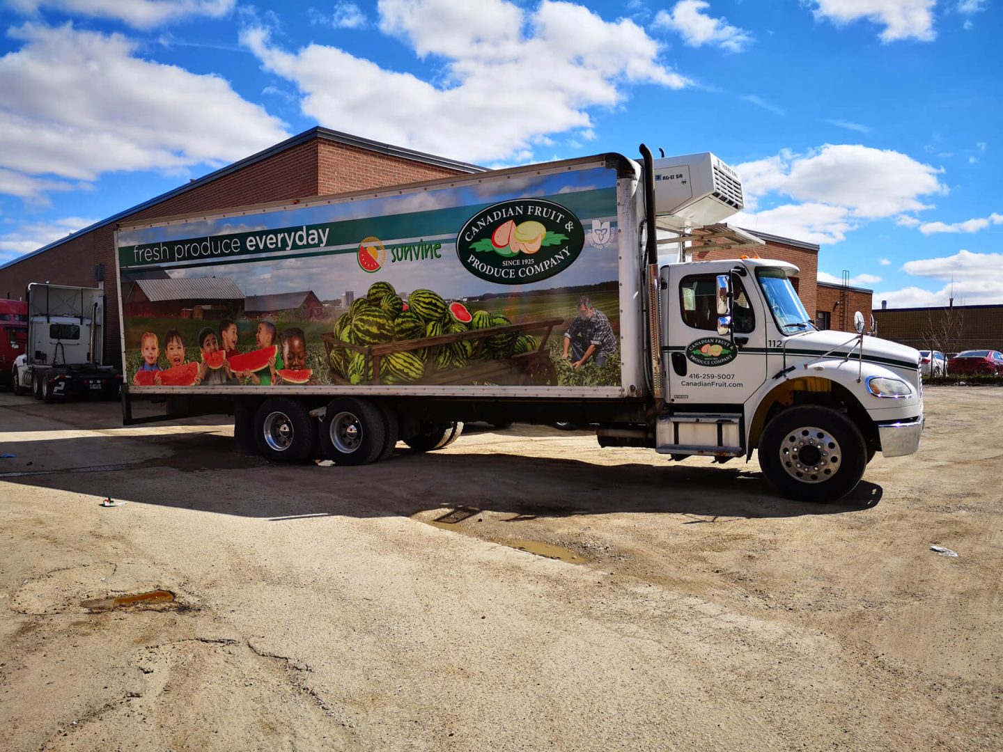 A truck branded with commercial vehicle graphics in the driveway